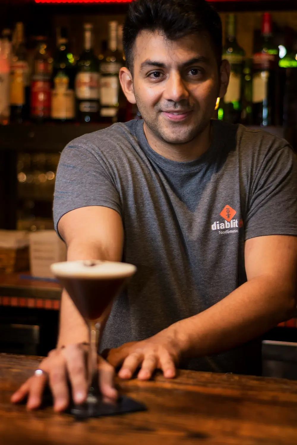 Alessandro Congedo, bartender e titolare del cocktail bar Gentleman a Lecce, mentre serve un espresso martini al bancone